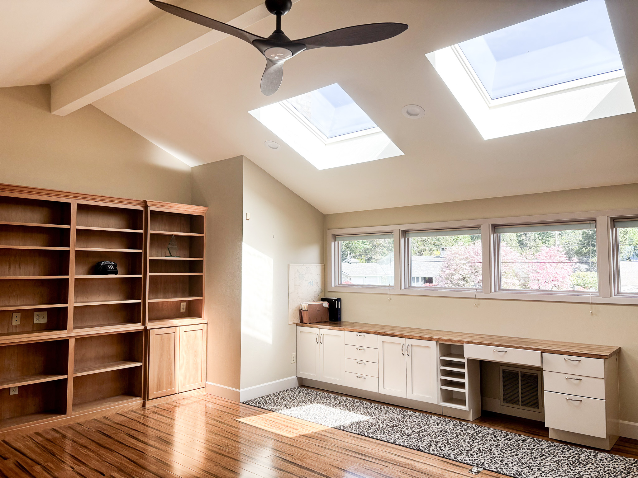 Office with custom built-in bookshelves, desk, dual skylights and ceiling fan